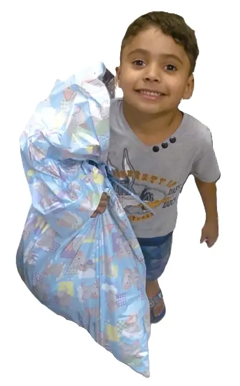 Criança sorrindo carregando um presente recebido.